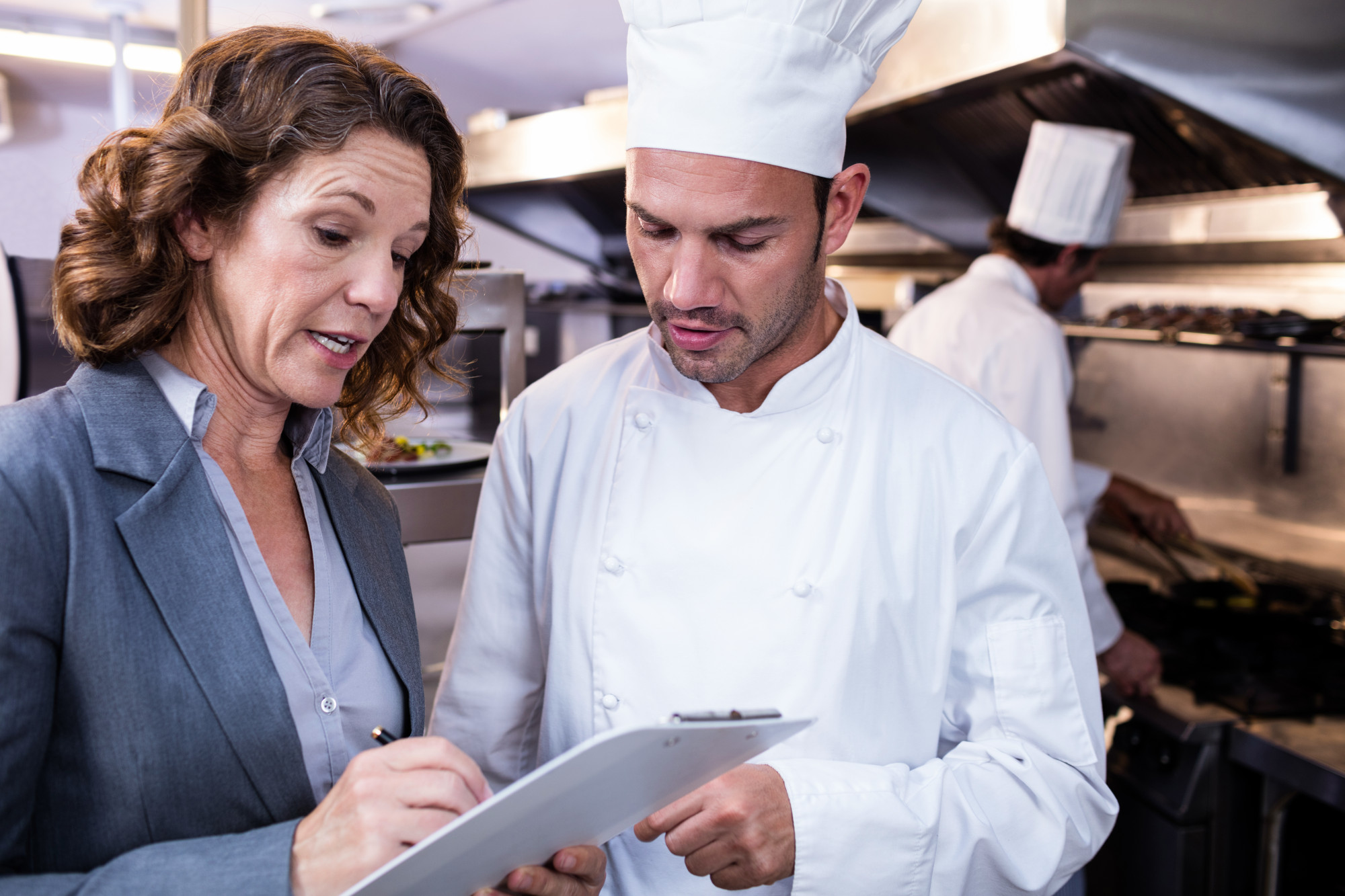 chef consulting with restaurant staff in kitchen
